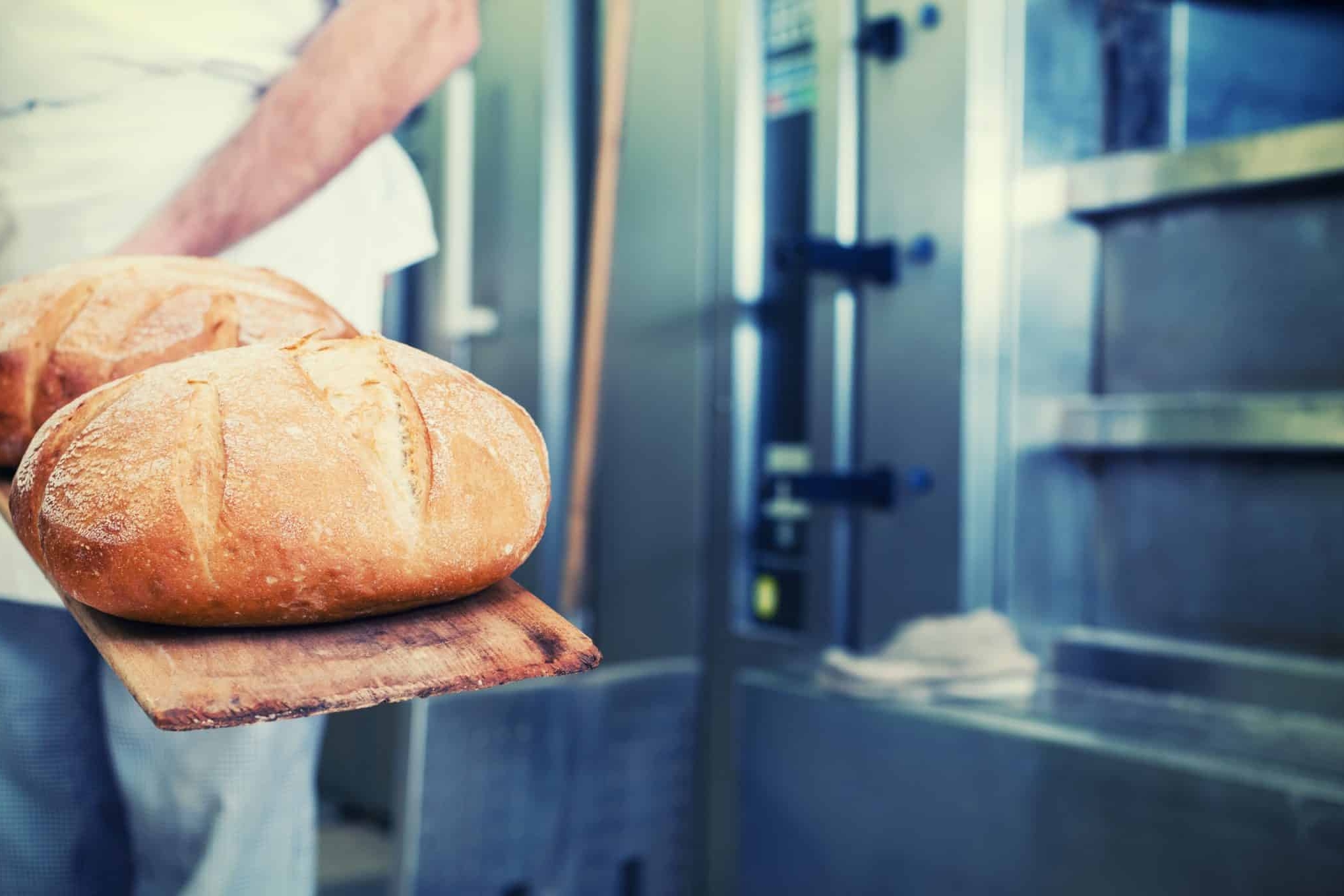 Bäcker steht mit Brot vor dem Ofen/ AdobeStock_100575082 Kzenon